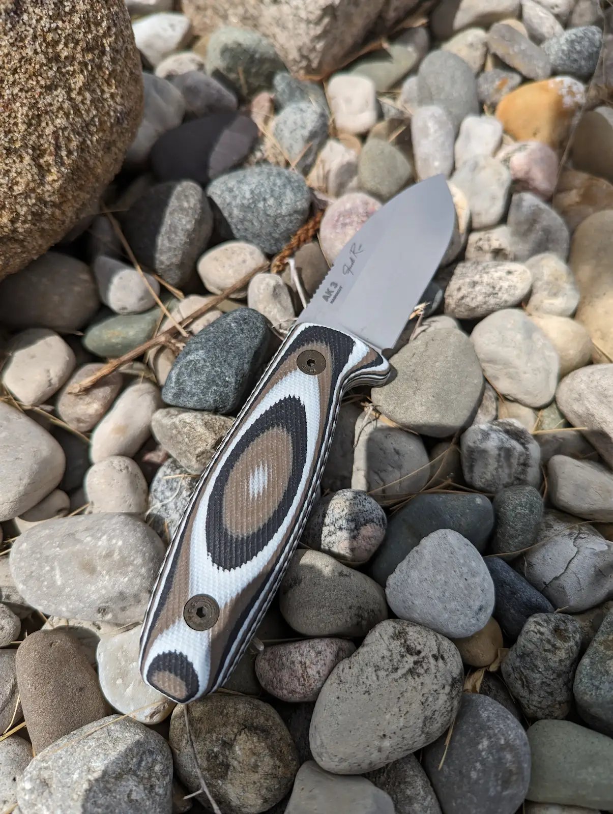 a knife with a white, black, and brown handle